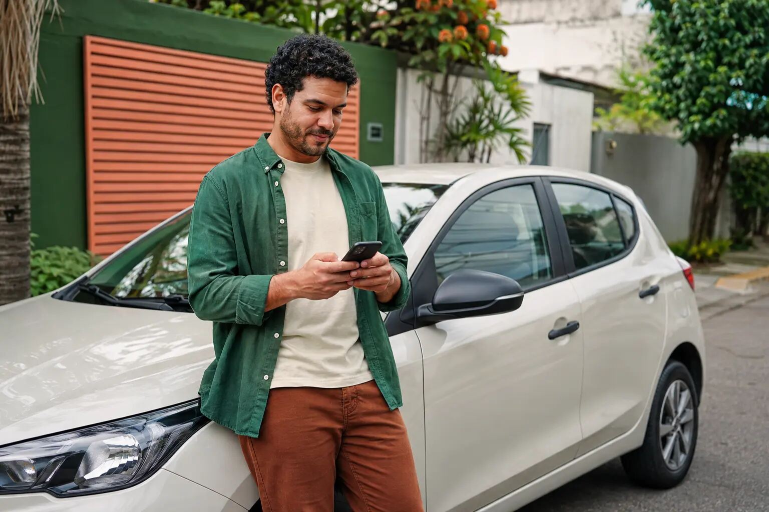 Proprietária consulta cotação de seguro ao lado de um carro compacto